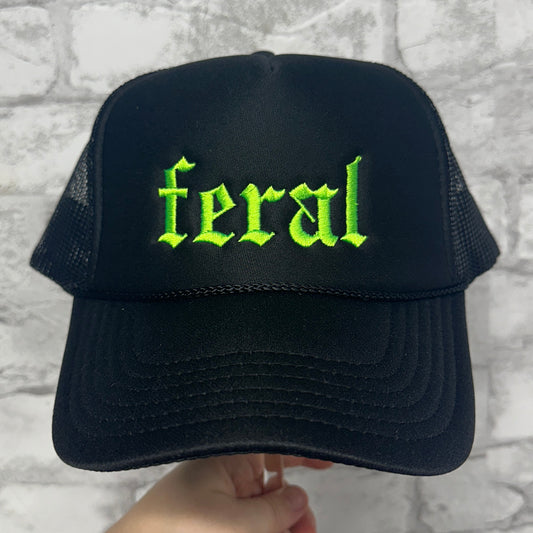 Black mesh trucker hat with neon green embroidered “feral” text on the front.