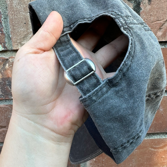 Adjustable strap and metal buckle on back of baseball cap.