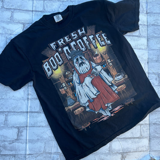 Black graphic T-shirt shown from the front, featuring a ghost barista illustration holding a coffee mug with the phrase “Fresh Boo'd Coffee” across the chest.