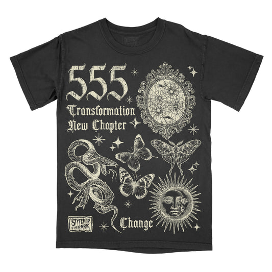 black T-shirt featuring a distressed 555 angel number design with a cracked mirror, snakes, butterflies, moth, and celestial sun, with text reading “Transformation,” “New Chapter,” and “Change,” plus Stitched in the Dark branding.
