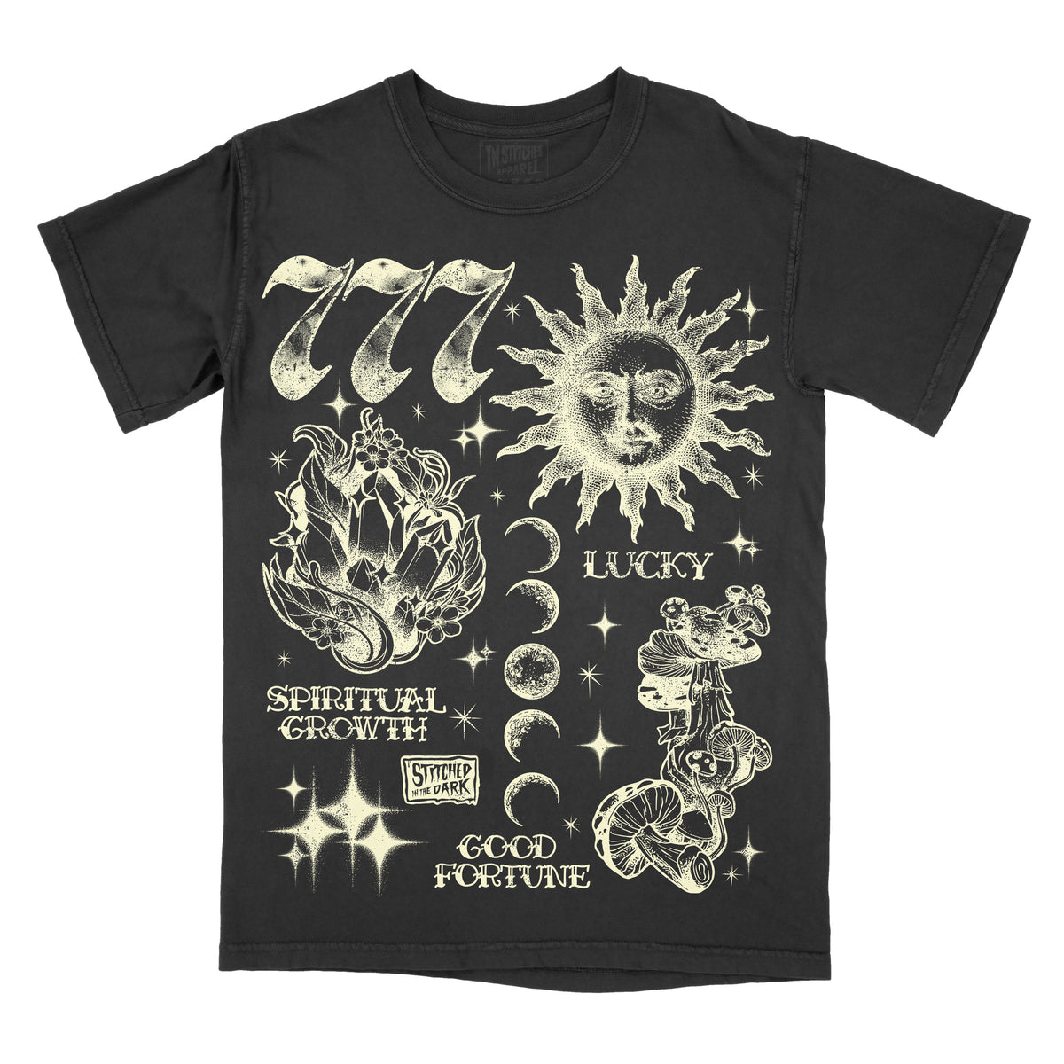 black T-shirt featuring a distressed 777 angel number design with a celestial sun, crystals, moon phases, mushrooms, and stars, with text reading “Lucky,” “Spiritual Growth,” and “Good Fortune,” plus Stitched in the Dark branding.