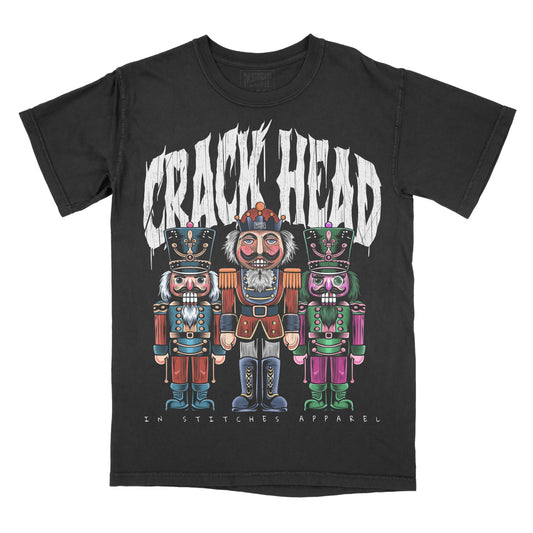 Black graphic tee with a design featuring cartoon-style nutcracker characters in colorful attire and the text 'CRACK HEAD'.