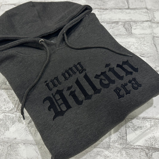 A dark gray hoodie with the phrase 'In My Villain Era' embroidered in black on the front.