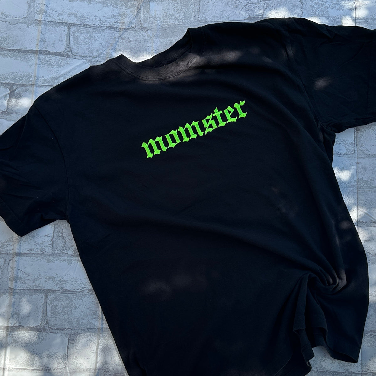 Black Comfort Colors embroidered t-shirt with the word 'momster' stitched in green on the front.