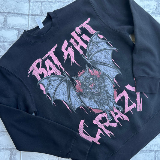 A black crewneck sweatshirt with a graphic print of bats and the text 'BAT SHIT CRAZY' in pink.