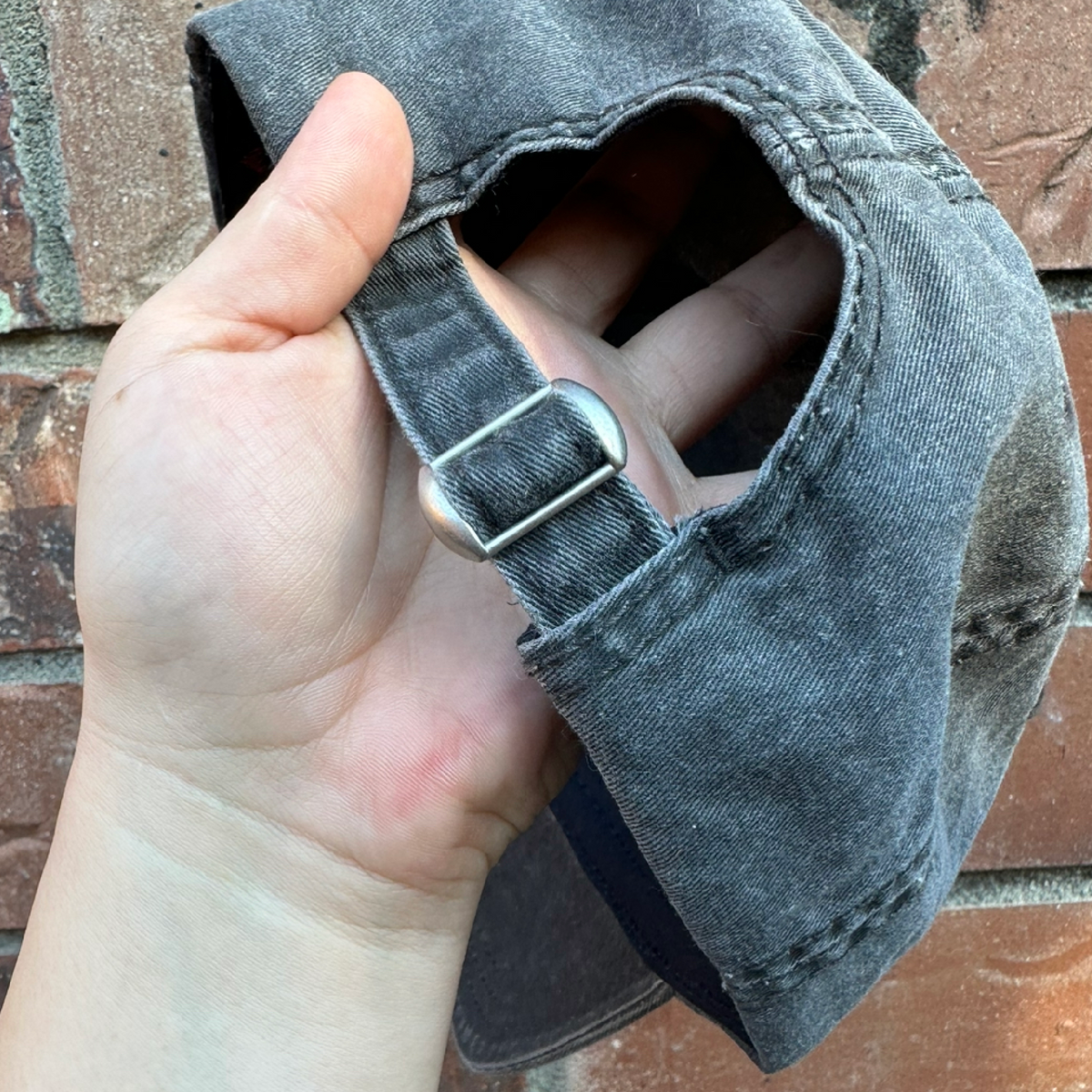 Adjustable strap and metal buckle on back of baseball cap.