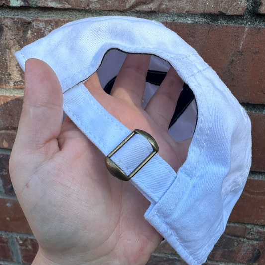 Back view of a distressed baseball cap showing adjustable fabric strap with metal buckle closure.