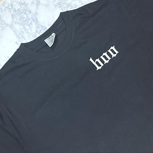 Black short-sleeve T-shirt laid flat, featuring small embroidered text reading “boo” on the chest.