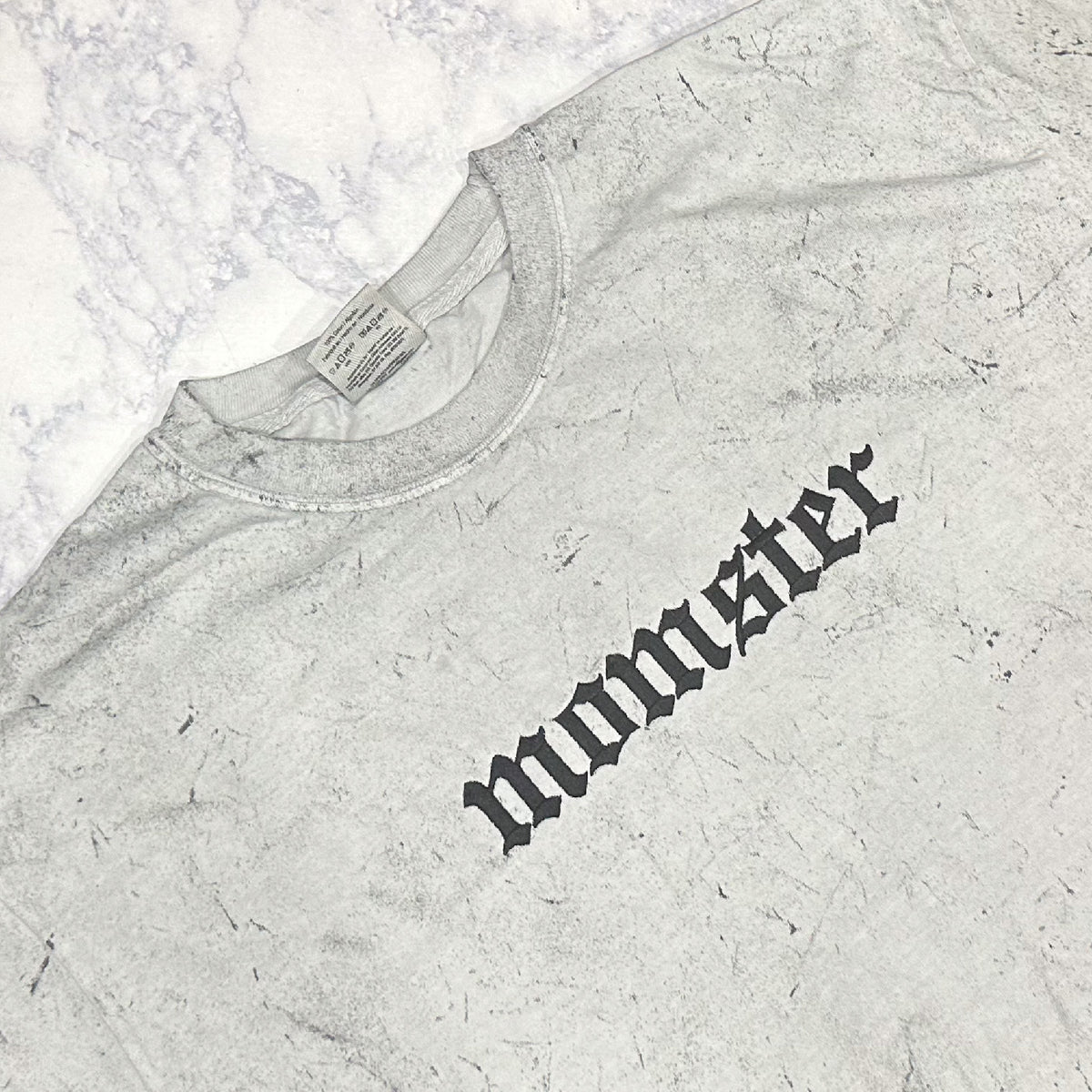 A Smoke Comfort Colors t-shirt with the word 'momster' embroidered in a stylized font.