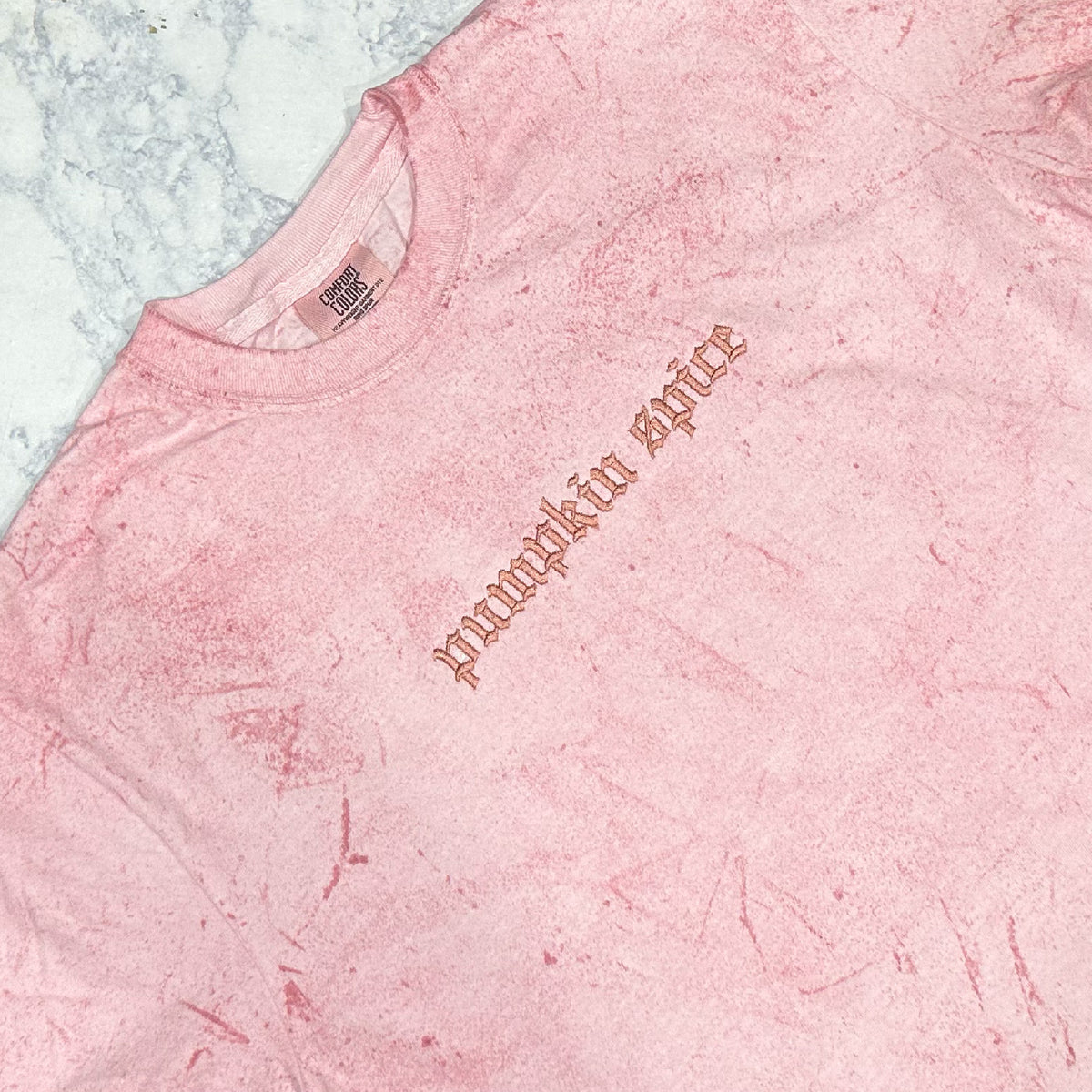 Light pink mineral-washed sweatshirt with monochromatic pink embroidery reading pumpkin spice.