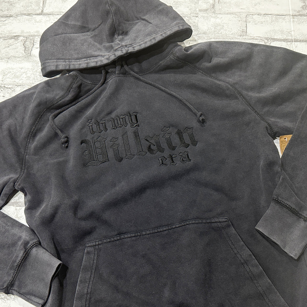 Vintage Black mineral-wash pullover layed folded flat, featuring black gothic lettering that reads ‘in my Villain era.