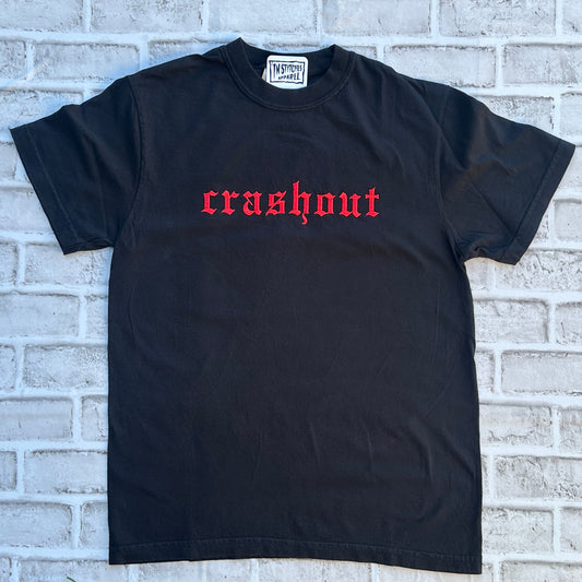 Black t-shirt with red text 'crashout' on a brick wall background