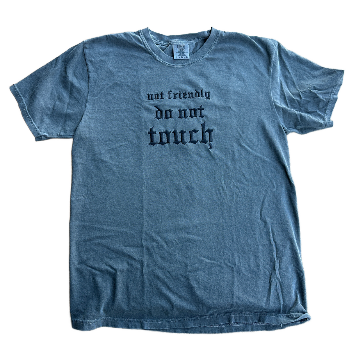 Pepper Comfort Colors short sleeve t-shirt featuring black Gothic-style embroidery reading “not friendly do not touch” across the center chest in three lines.