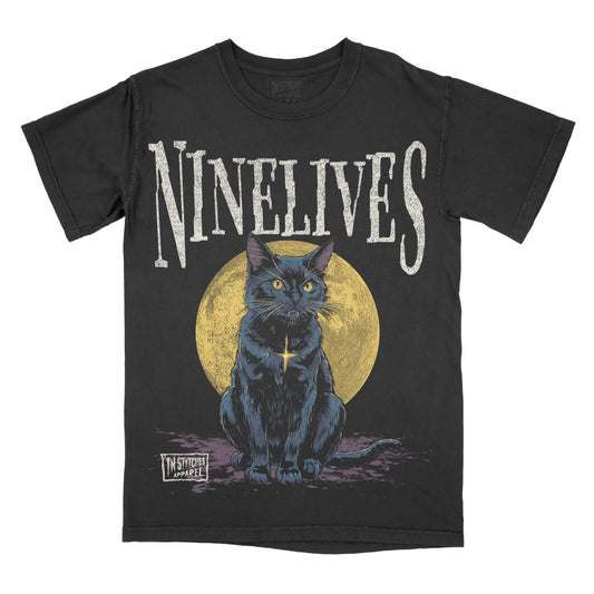 Black graphic t-shirt featuring the word “Ninelives” above an illustration of a blue cat sitting in front of a yellow moon with a distressed, gothic-style design.
