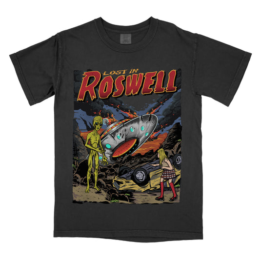Black t-shirt  featuring a retro sci-fi graphic with an alien, a flying saucer, and a desert scene, with ‘Lost in Roswell’ text above the artwork.