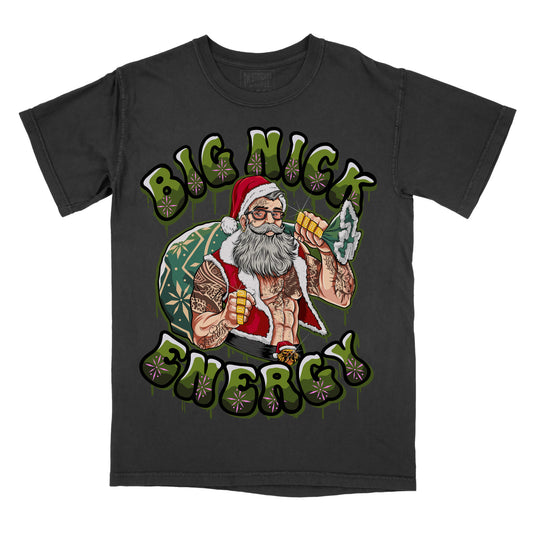 black T-shirt featuring an illustrated Santa Claus holding a drink and a sack, with the text ‘Big Nick Energy’ in green lettering.”