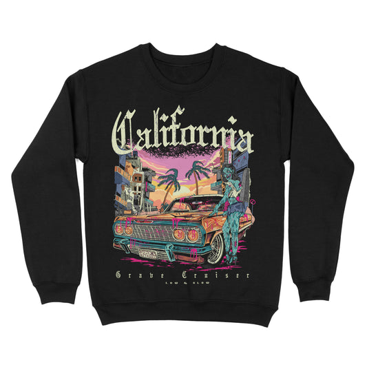 Black sweatshirt featuring a California-themed graphic with a lowrider car, palm trees, urban buildings, and sunset colors, with “California” text above the artwork.