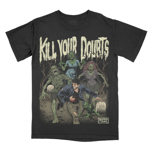 Black vintage-wash graphic T-shirt featuring the phrase "Kill Your Doubts" above a man running from a horde of zombies through a graveyard. The horror-inspired artwork includes undead figures, tombstones, dead trees, and a dark apocalyptic atmosphere.