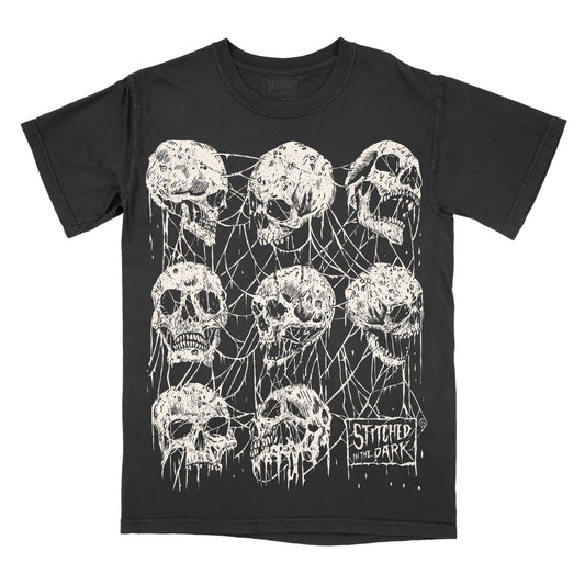 Black vintage wash T-shirt featuring a distressed Webbed Skulls graphic with white skulls tangled in spiderwebs and Stitched in the Dark branding.