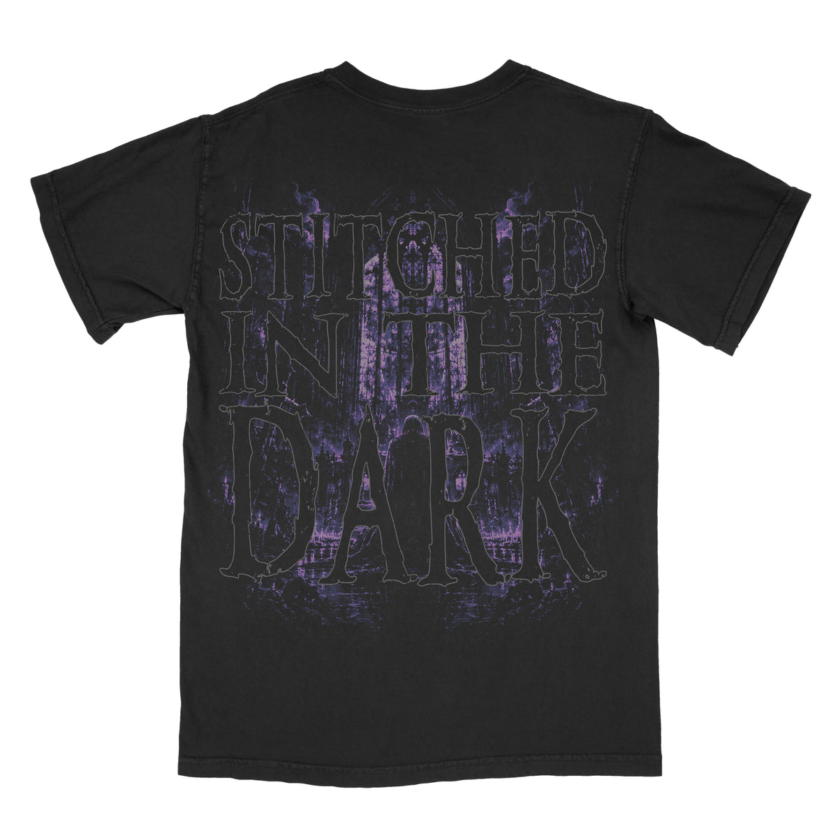 Back of a black vintage-wash graphic tee featuring oversized distressed “Stitched in the Dark” lettering over a shadowy gothic forest scene in dark purple and lavender tones.