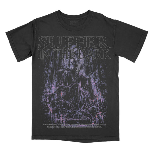 Black vintage-wash graphic tee featuring “Suffer in the Dark” across the chest above a shadowy gothic figure seated in a dark forest, illustrated in distressed purple, lavender, and muted pink tones.