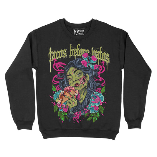 Black crewneck sweatshirt with the phrase ‘Tacos Before Vatos’ above a colorful gothic illustration of a woman holding a taco surrounded by flowers