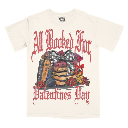 Cream graphic tee with 'All Booked For Valentine's Day' text and book-themed illustrations including a bow, flowers, and a shelf of books.
