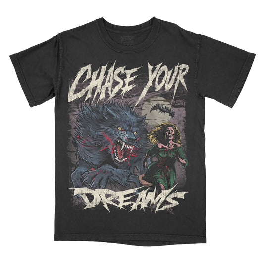 A black graphic tee with a design featuring a stylized wolf and a person, and the text 'CHASE YOUR DREAMS' printed above.